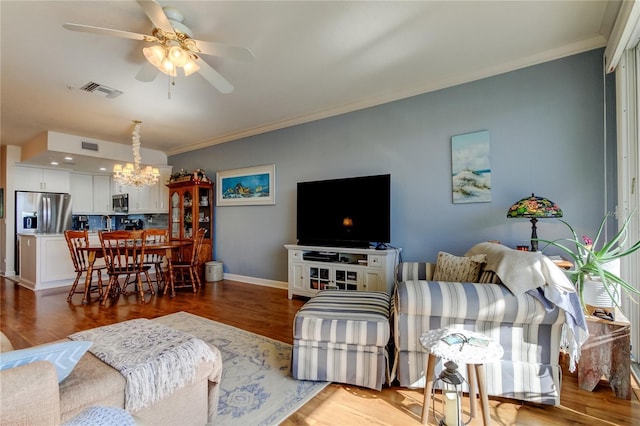 living room with baseboards, light wood finished floors, visible vents, crown molding, and ceiling fan with notable chandelier