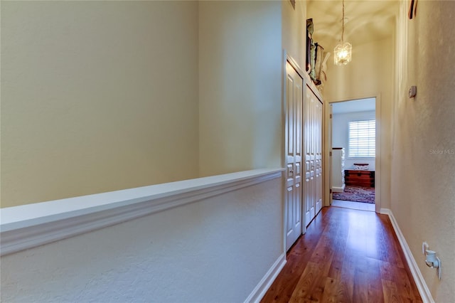 corridor featuring dark wood-type flooring and baseboards