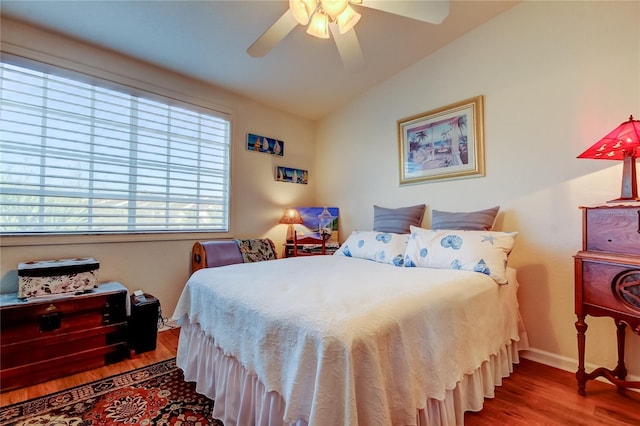 bedroom featuring lofted ceiling, wood finished floors, baseboards, and ceiling fan