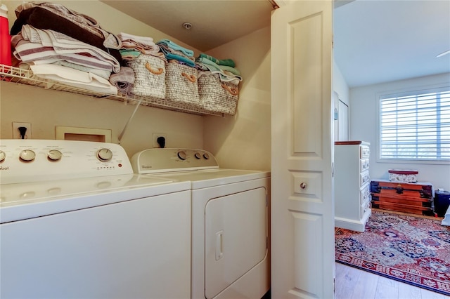 washroom with wood finished floors, washing machine and dryer, and laundry area