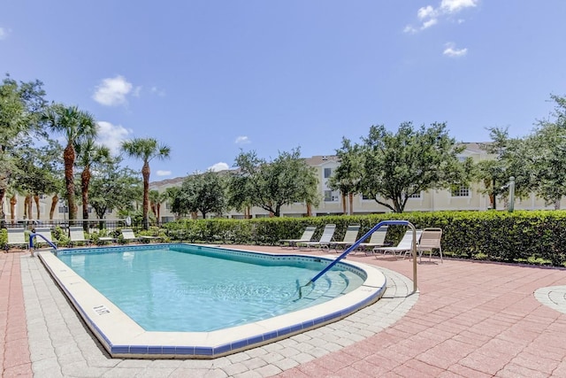 community pool with a patio and fence