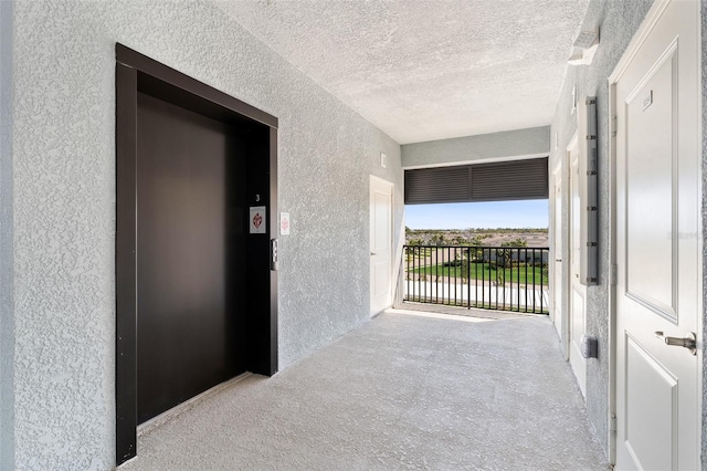 interior space with elevator, a textured ceiling, and a textured wall