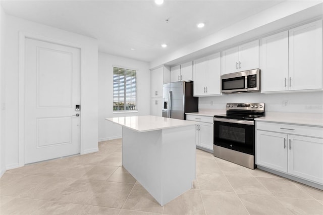 kitchen featuring a center island, light countertops, light tile patterned floors, appliances with stainless steel finishes, and white cabinetry