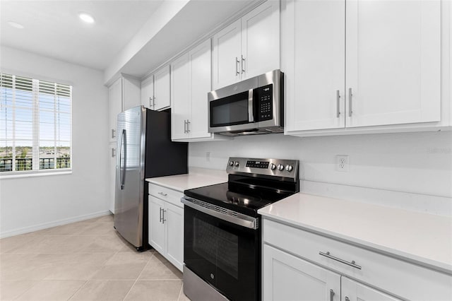 kitchen featuring baseboards, light countertops, light tile patterned floors, appliances with stainless steel finishes, and white cabinets