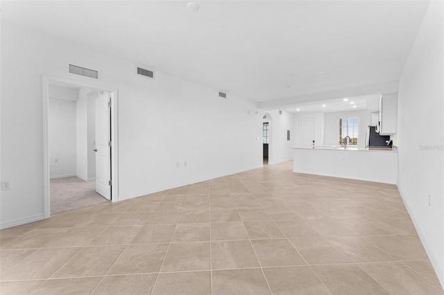 unfurnished living room with arched walkways, visible vents, and a sink