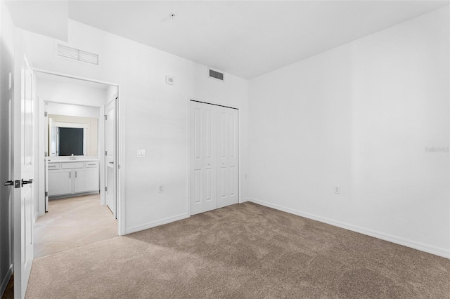 unfurnished bedroom with baseboards, visible vents, a closet, and light carpet