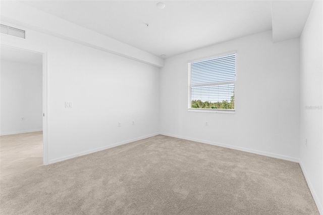 empty room with visible vents, light colored carpet, and baseboards