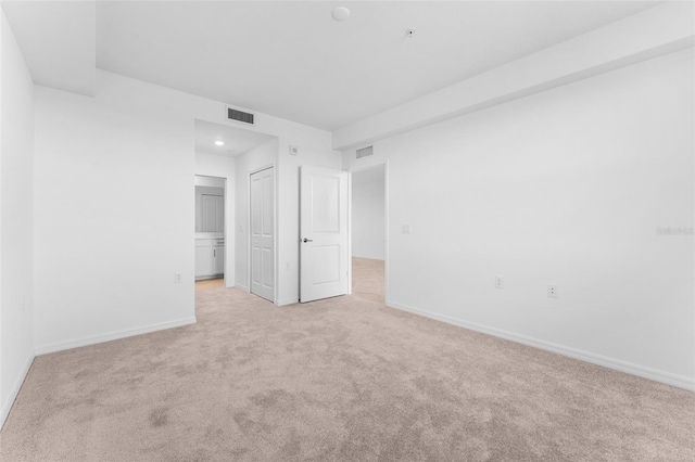 unfurnished bedroom featuring baseboards, visible vents, and light carpet