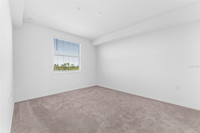 carpeted spare room featuring baseboards