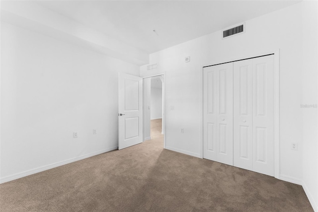 unfurnished bedroom with carpet flooring, baseboards, visible vents, and a closet