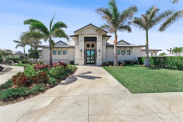 view of front facade with french doors, a front yard, a standing seam roof, and metal roof