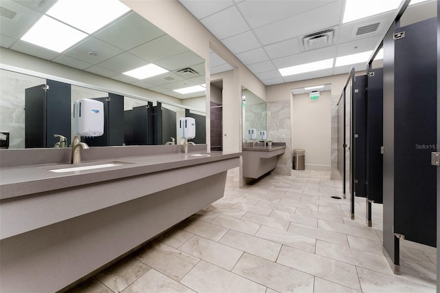 full bath with double vanity, visible vents, a drop ceiling, and a sink