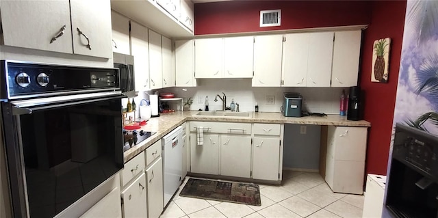 kitchen with a sink, visible vents, white cabinetry, light countertops, and black appliances