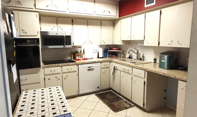 kitchen with light tile patterned floors, a sink, visible vents, decorative backsplash, and black appliances