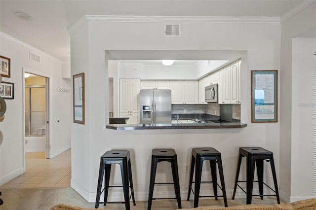 kitchen featuring visible vents, white cabinets, dark countertops, appliances with stainless steel finishes, and a peninsula