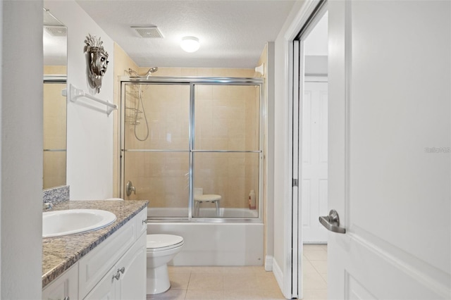 bathroom featuring a textured ceiling, toilet, shower / bath combination with glass door, vanity, and tile patterned floors