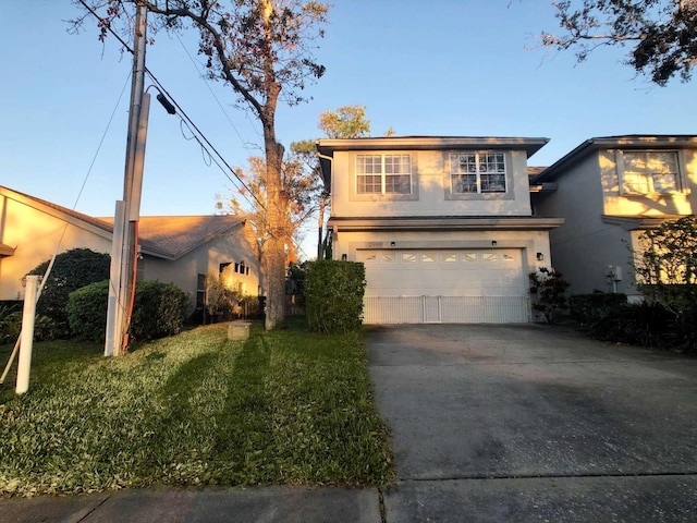 view of front facade with a garage, driveway, a front lawn, and stucco siding