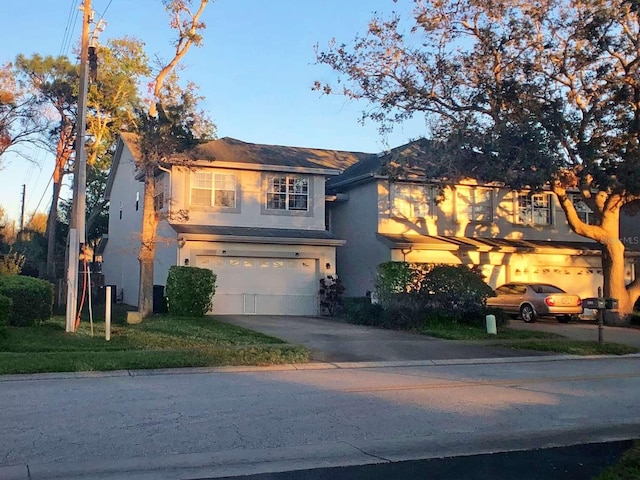 traditional-style home with driveway, an attached garage, and stucco siding