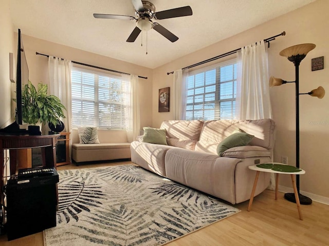 living room with ceiling fan, baseboards, light wood-style flooring, and a healthy amount of sunlight