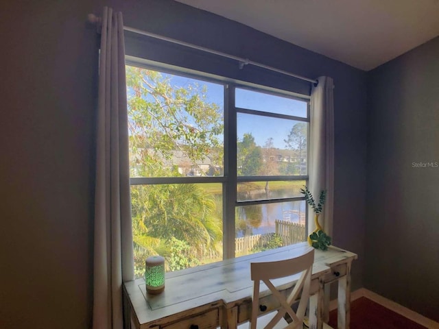 dining space featuring a water view and baseboards