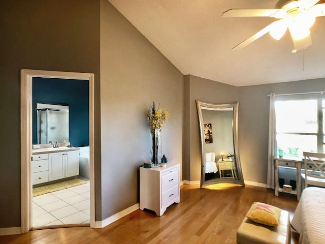 living area with light wood-style flooring, vaulted ceiling, baseboards, and ceiling fan