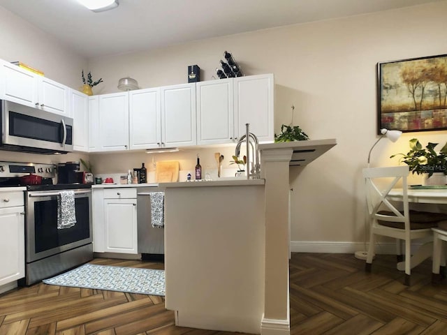 kitchen featuring white cabinets, baseboards, stainless steel appliances, and light countertops