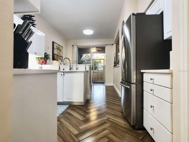 kitchen with a peninsula, white cabinetry, baseboards, light countertops, and freestanding refrigerator