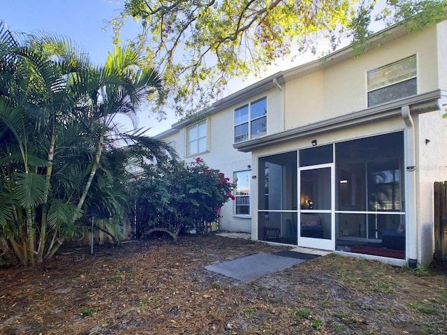 rear view of property featuring a sunroom and stucco siding