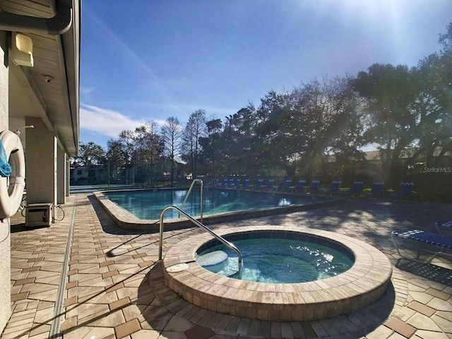 community pool with a patio area and a hot tub