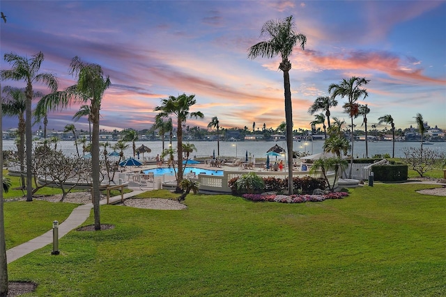 exterior space with a water view, a pool, and a lawn