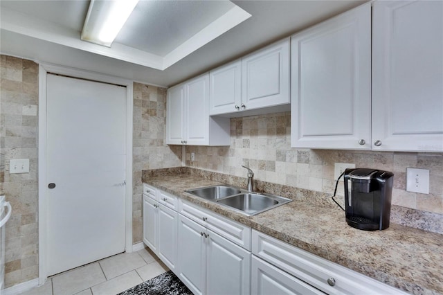 kitchen with light tile patterned flooring, a sink, and white cabinets