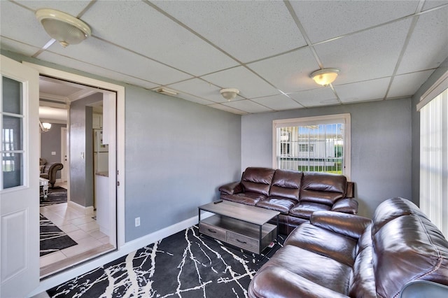 living room featuring a paneled ceiling and baseboards