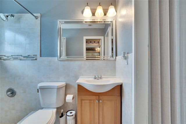 bathroom with a shower, tile walls, vanity, and toilet