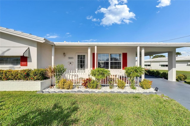 ranch-style house with driveway, an attached carport, a front yard, and stucco siding