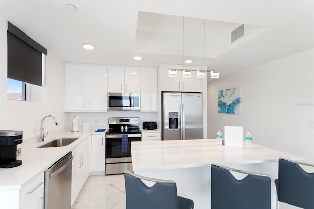 kitchen featuring modern cabinets, appliances with stainless steel finishes, marble finish floor, a kitchen bar, and a sink