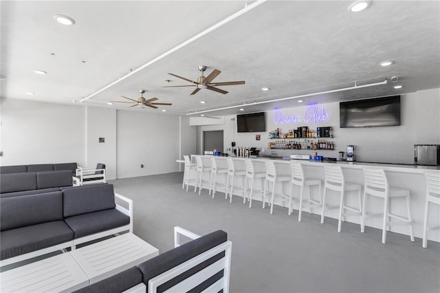 living room featuring concrete floors, a ceiling fan, indoor wet bar, and recessed lighting