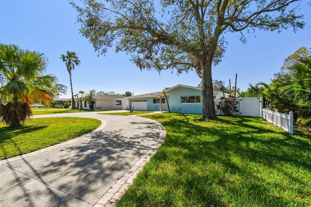 view of front of home with a front yard, curved driveway, stucco siding, and fence