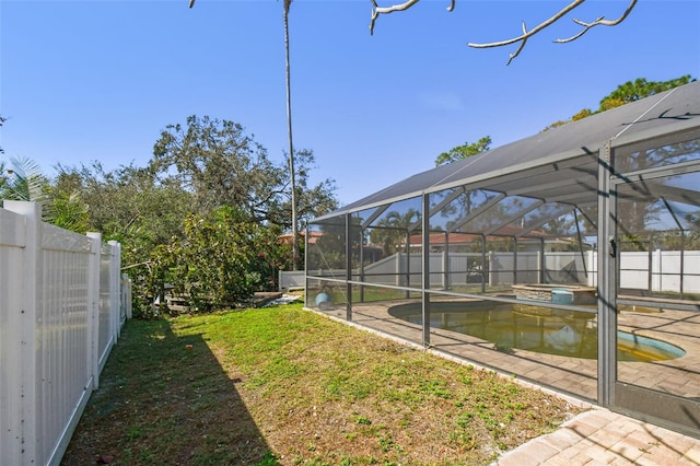view of yard with glass enclosure, a fenced backyard, a pool with connected hot tub, and a patio area