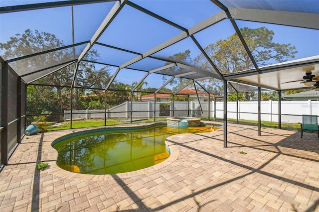 view of swimming pool featuring a fenced backyard, a pool with connected hot tub, glass enclosure, and a patio