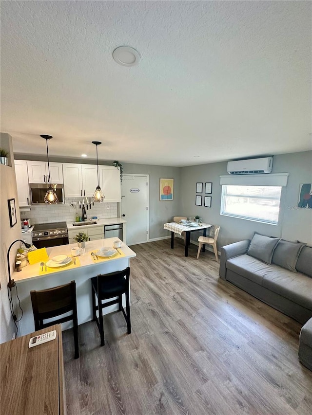 dining area featuring a textured ceiling, wood finished floors, and a wall mounted air conditioner