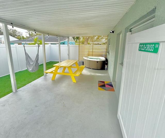 view of patio with a hot tub and fence