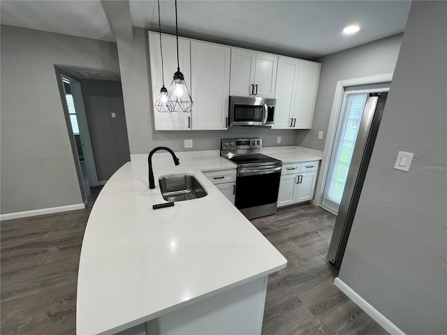 kitchen with dark wood-style floors, appliances with stainless steel finishes, a sink, and white cabinets