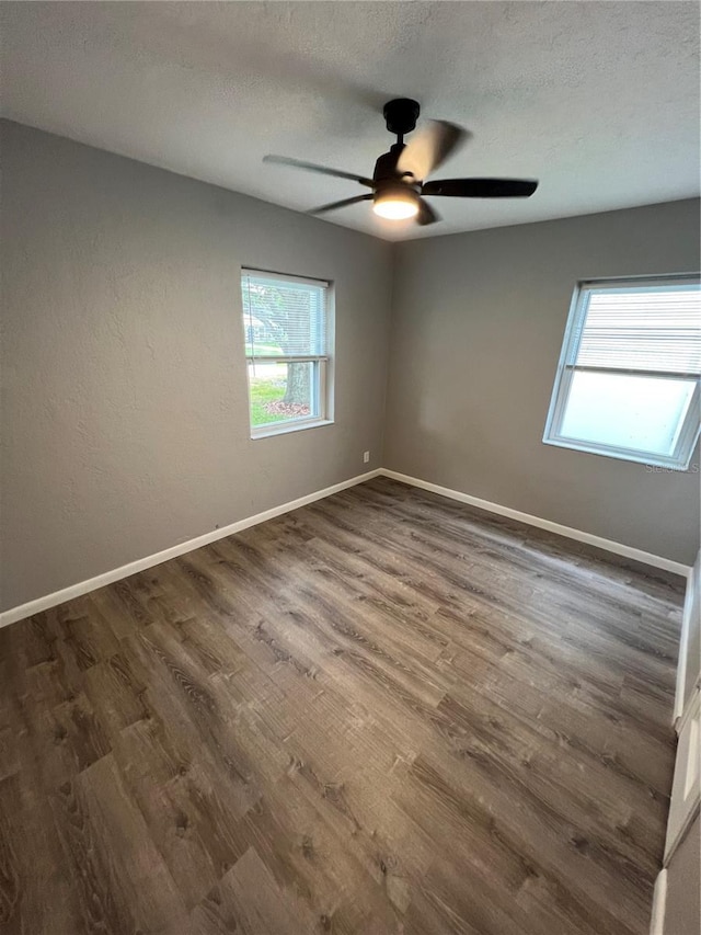 spare room with a textured ceiling, dark wood-style flooring, a ceiling fan, and baseboards