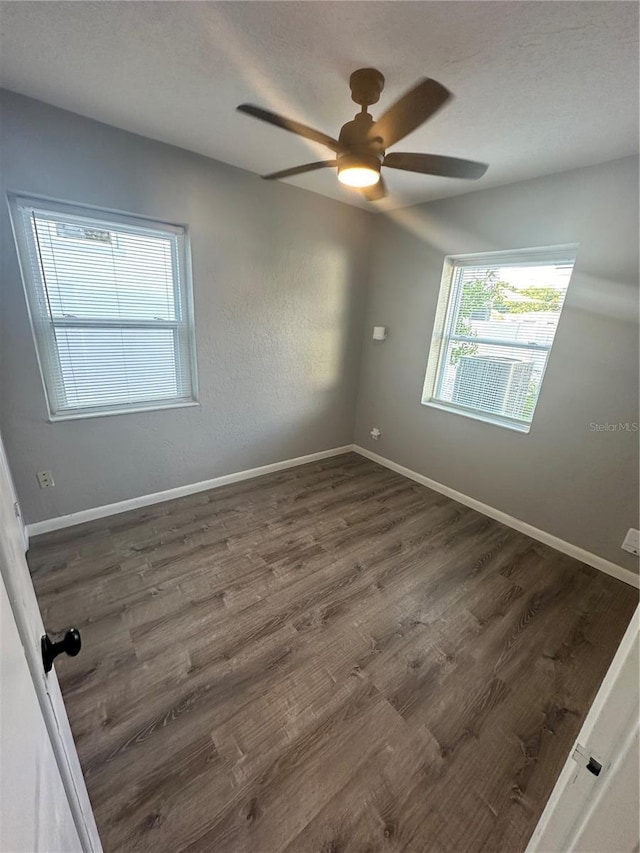 spare room with ceiling fan, dark wood finished floors, and baseboards