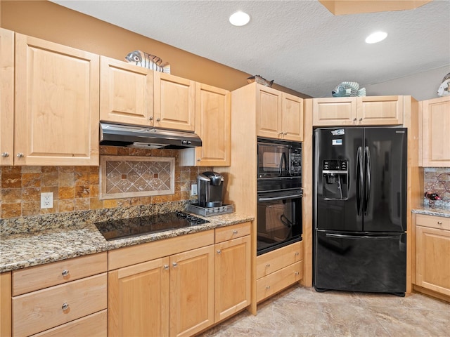 kitchen featuring light brown cabinetry, under cabinet range hood, black appliances, and light stone countertops