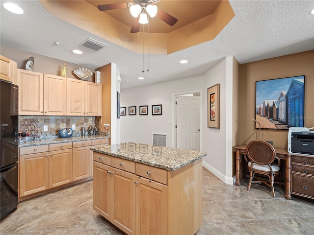 kitchen featuring light brown cabinetry, a raised ceiling, visible vents, and light stone countertops