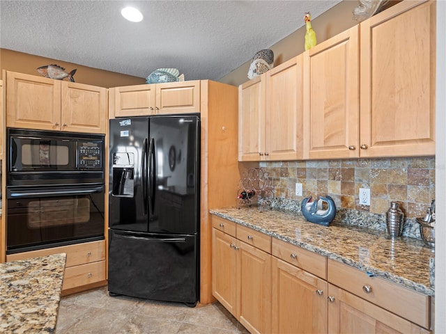 kitchen featuring tasteful backsplash, light stone countertops, a textured ceiling, light brown cabinetry, and black appliances