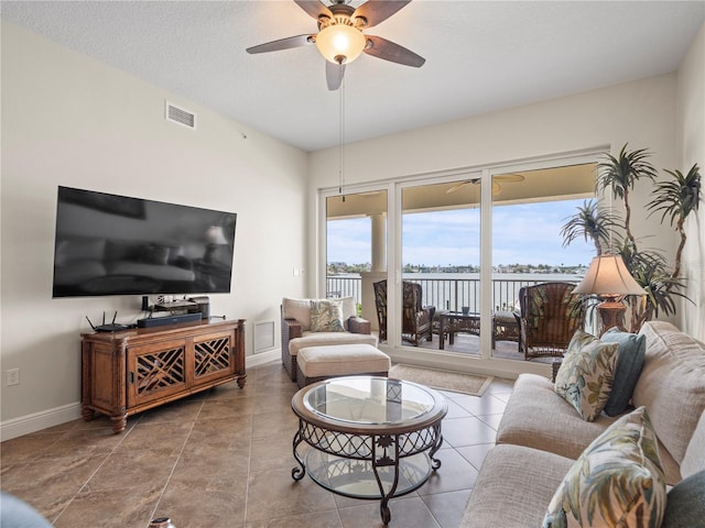 living room with ceiling fan, tile patterned floors, visible vents, and baseboards