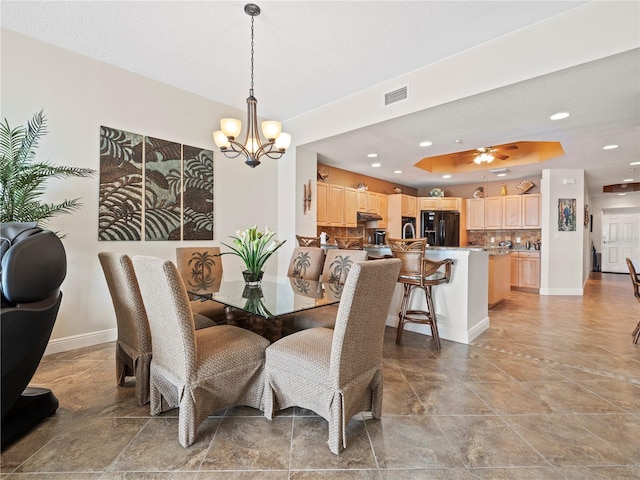 dining space featuring a tray ceiling, recessed lighting, visible vents, baseboards, and ceiling fan with notable chandelier