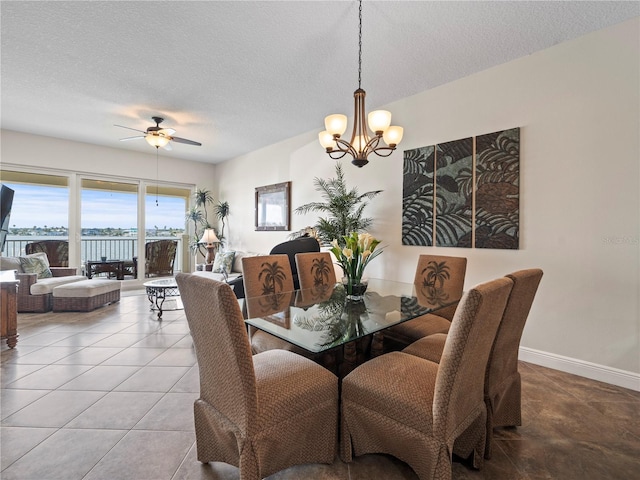 dining area featuring tile patterned flooring, a textured ceiling, baseboards, and ceiling fan with notable chandelier